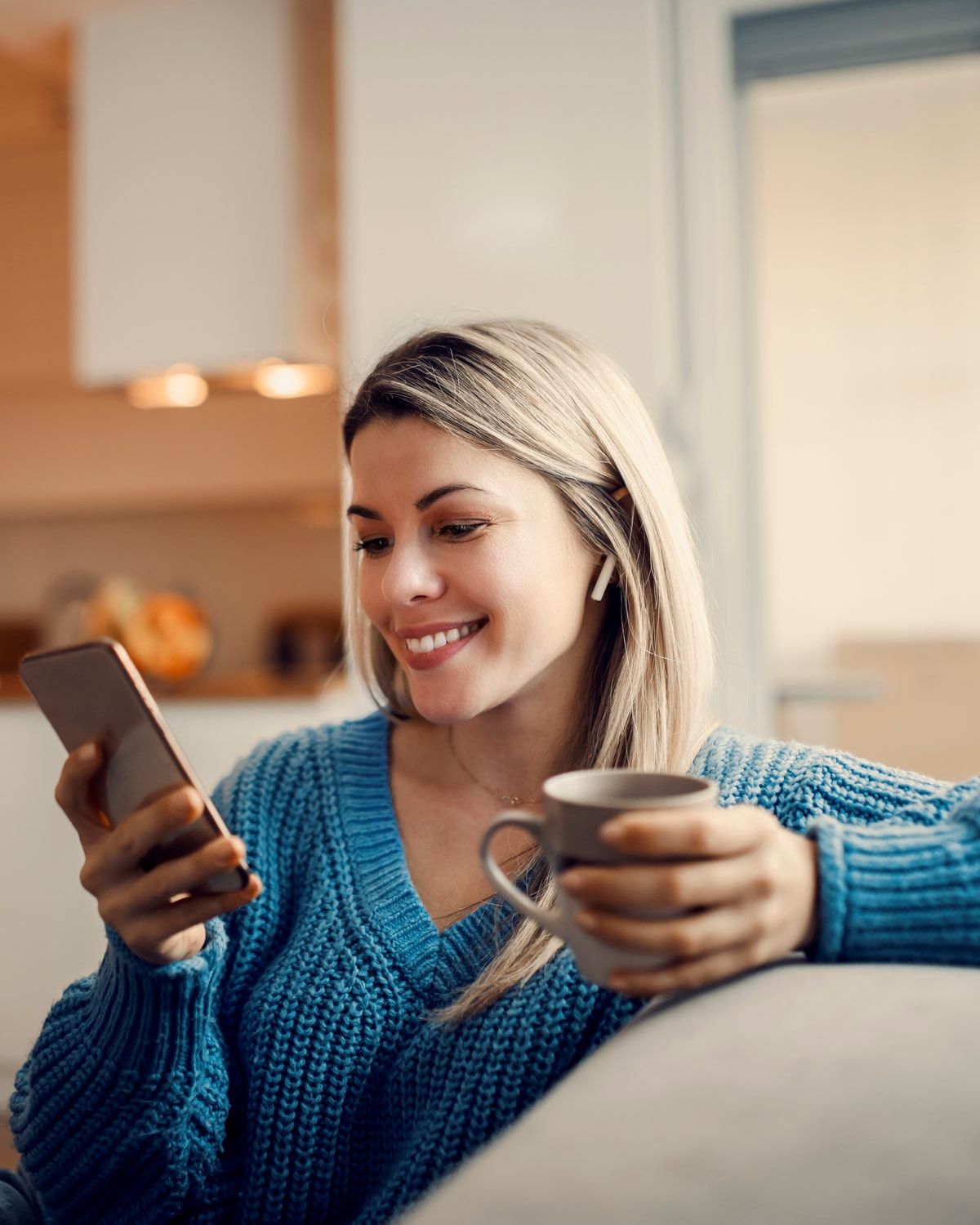 A woman relaxing on her couch with coffee, checking the week’s dinner plan on her phone.